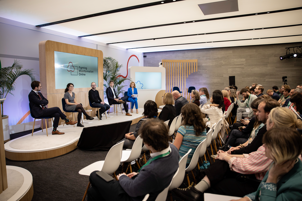 5 people on stage participating in a fireside chat in front of an audience.