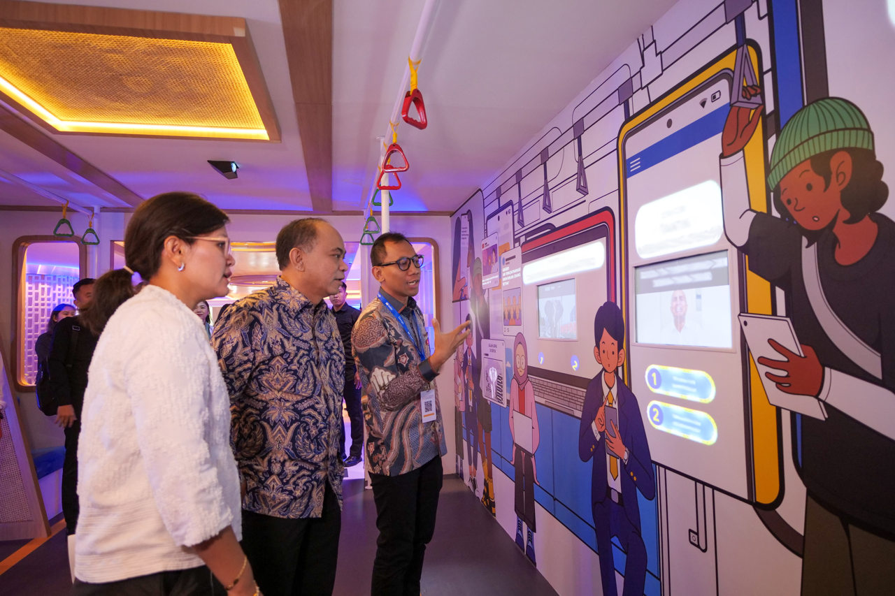 Three people reading off a cartoon phone display on the wall.