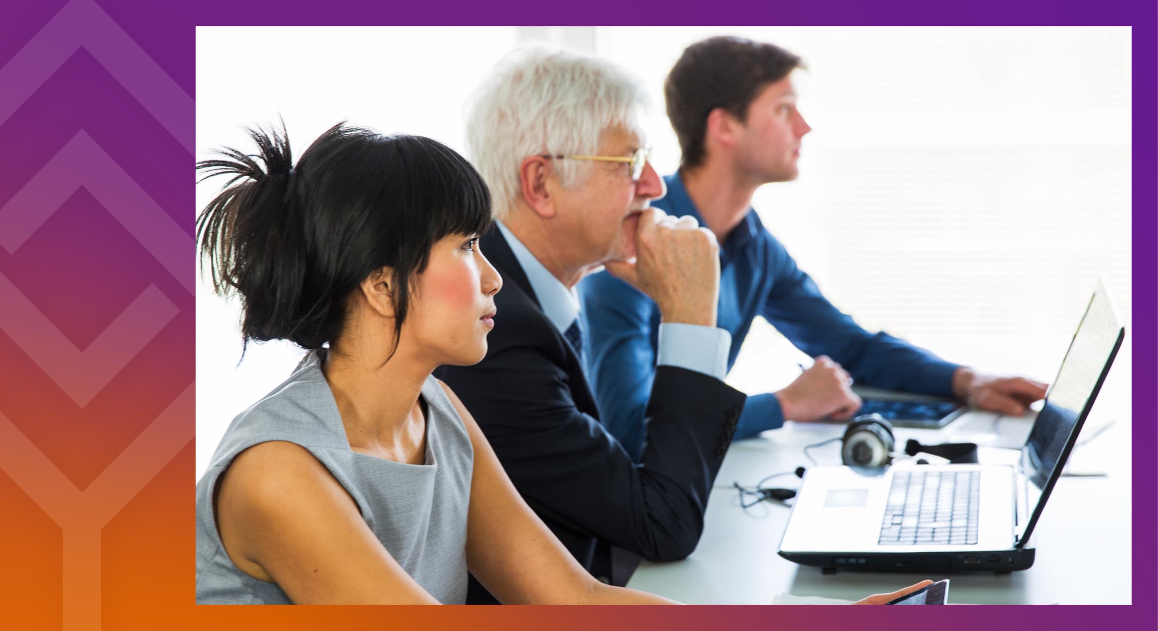 Three people sitting at a desk listening to a speaker