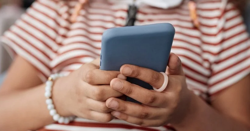 A close up of a child's hands holding a smartphone.