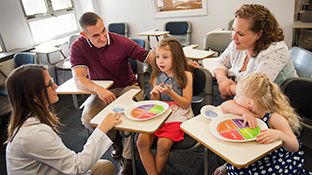 A student nutritionist talks to two children and their parents