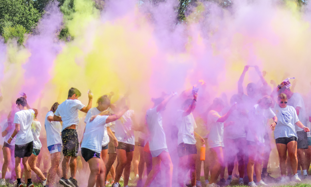 students throwing purple and yellow powder in the sky