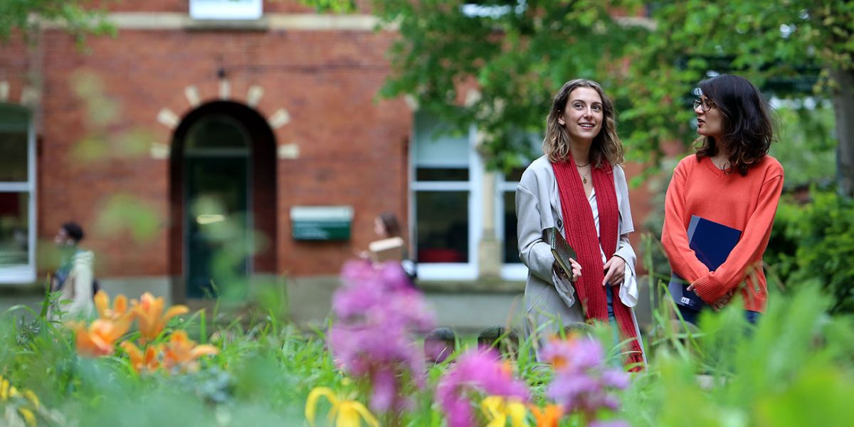 Postgraduate students outside Clothworker's Court with bright flowers in the foreground