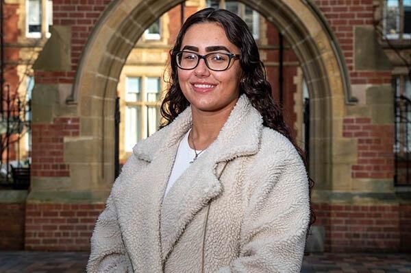 Student, Shanese Youngs, stood outside the Great Hall wearing a white coat.