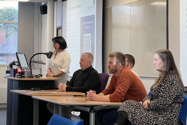 Five presenters on a panel, with one lasy standing and four people sitting, at a COIL event.