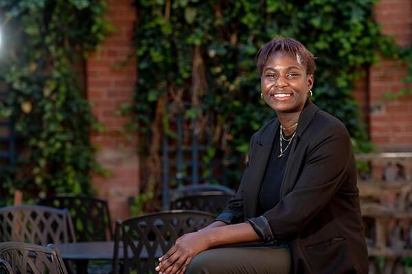 Student, Pearls Eddo, sitting outside the Great Hall wearing a black blazer