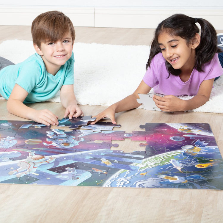 A kid playing with The Melissa & Doug Outer Space Glow-in-the-Dark Cardboard Jigsaw Floor Puzzle – 48 Pieces, for Boys and Girls 3+