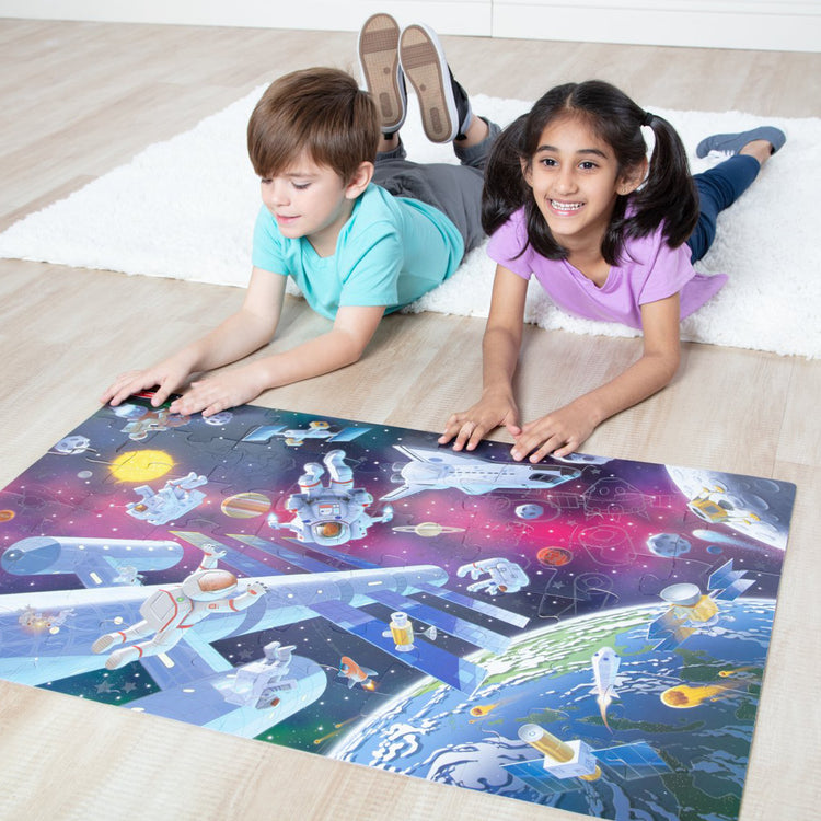 A kid playing with The Melissa & Doug Outer Space Glow-in-the-Dark Cardboard Jigsaw Floor Puzzle – 48 Pieces, for Boys and Girls 3+