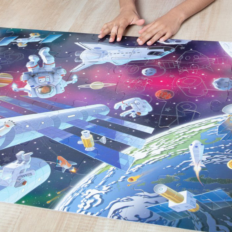 A kid playing with The Melissa & Doug Outer Space Glow-in-the-Dark Cardboard Jigsaw Floor Puzzle – 48 Pieces, for Boys and Girls 3+