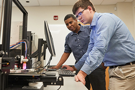 two male students lean over looking at computer alt Computers and Technology