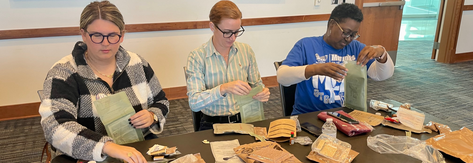 Three people are preparing envelopes for mailing