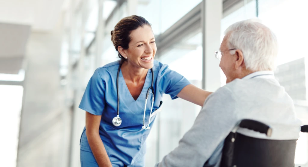 A healthcare worker talking to an older adult in a wheelchair