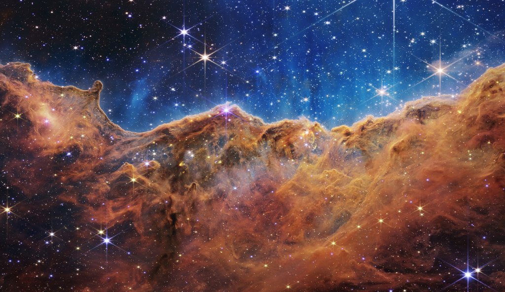 This landscape of “mountains” and “valleys” speckled with glittering stars is actually the edge of a nearby, young, star-forming region called NGC 3324 in the Carina Nebula. Captured in infrared light by NASA’s new James Webb Space Telescope, this image reveals for the first time previously invisible areas of star birth.