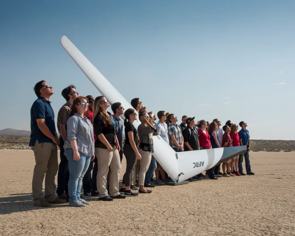 Student interns and NASA personnel cluster in front of PRANDTL-D No. 3 following a crash on Rosamond Dry Lake.