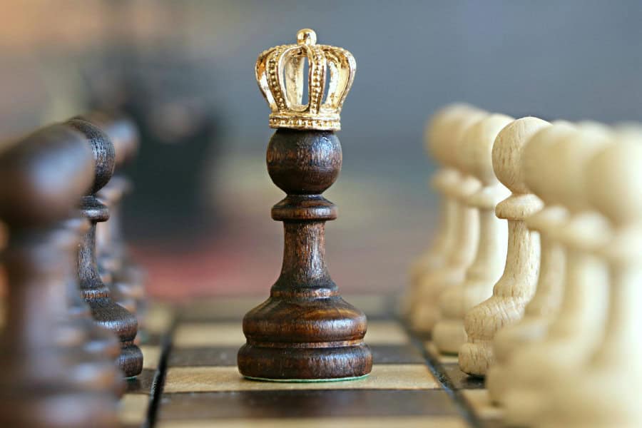 Gold crown on a pawn Chess piece with pawns lined up on either side