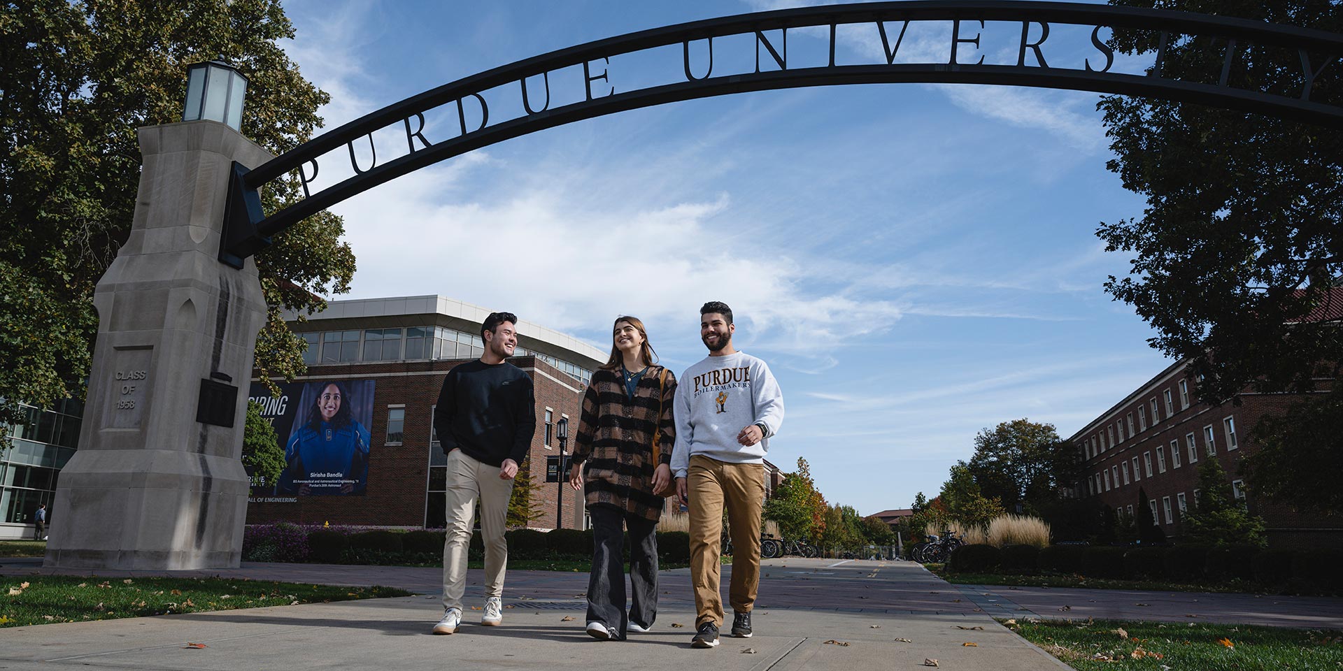 Purdue University students walking under arch on campus.