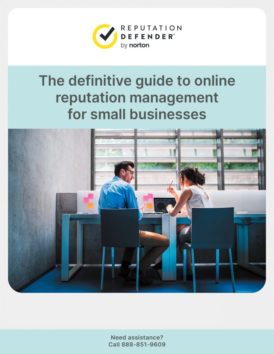 A man and woman discussing something while sitting at side-by-side desks.