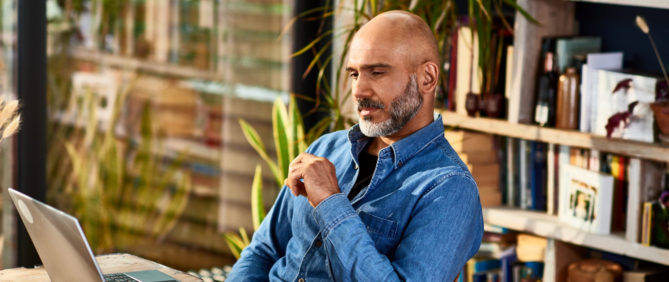 Handsome entrepreneur concentrating during virtual meeting on laptop, working from home, technology, connection