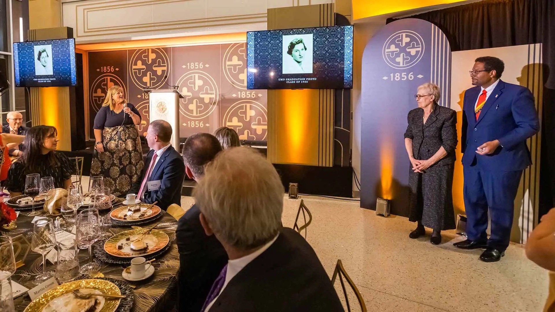 University leaders including Vice President for Student Affairs Patty Perillo (at left holding microphone) and President Darryll J. Pines (far right) honor Anna Karavangelos ’56 at an 1856 Society event last fall