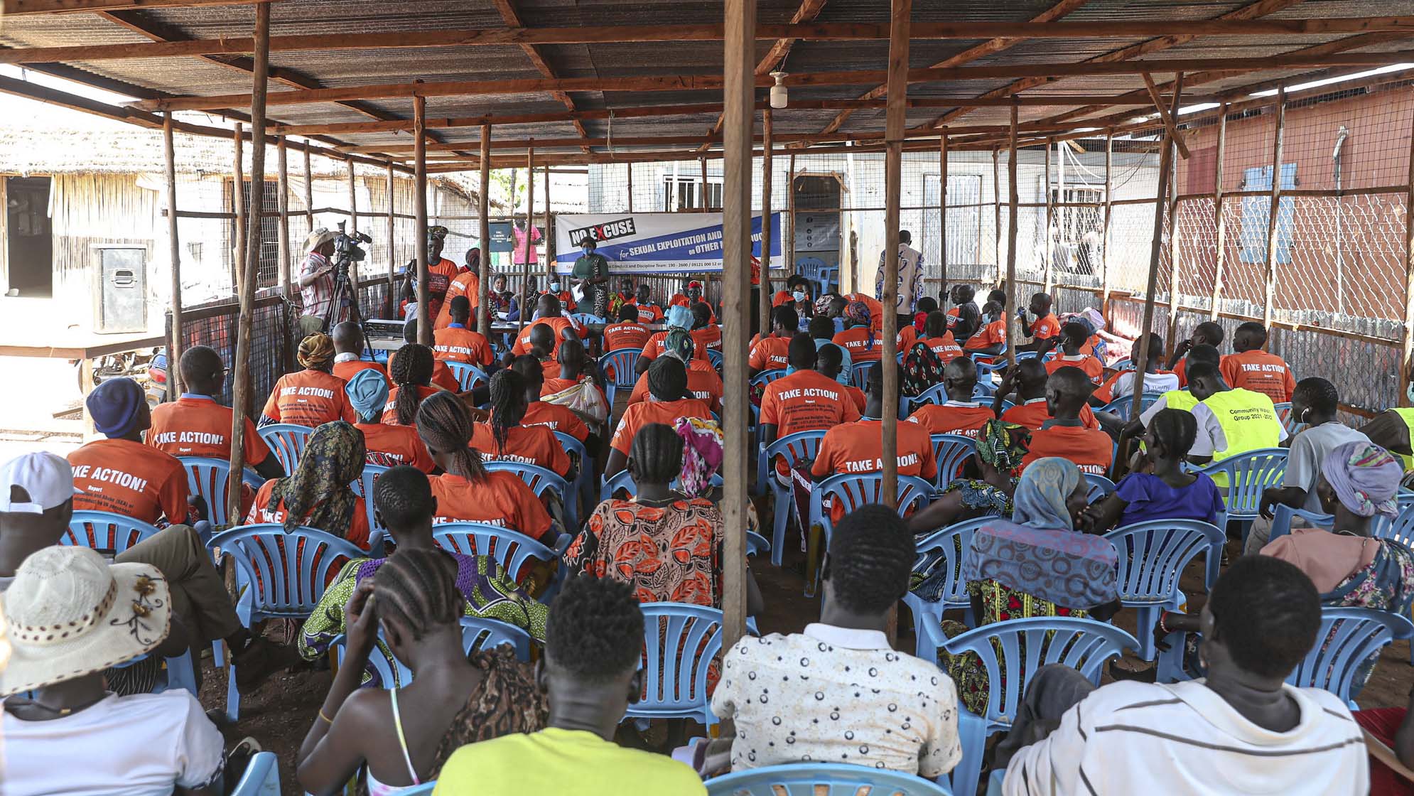 audience seen from the back in makeshift structure