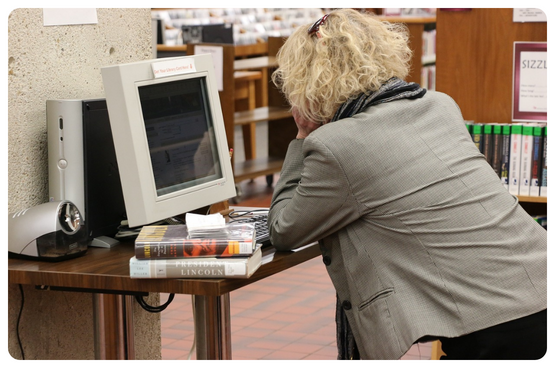 Picture of a teacher searching for something in a laptop at a library