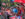 People watching the Puerto Rican Day Parade wave handheld Puerto Rican flags while standing behind a metal fence.