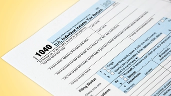 The top left corner of a Form 1040—U.S. Individual Income Tax Return—on a yellow background. The form has block tex and some text is highlighted with light blue boxes.