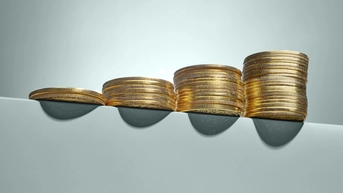 Progressively larger stacks of coins on a green table. The background is also green.