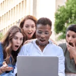 Group of people look shocked while looking at a laptop screen.